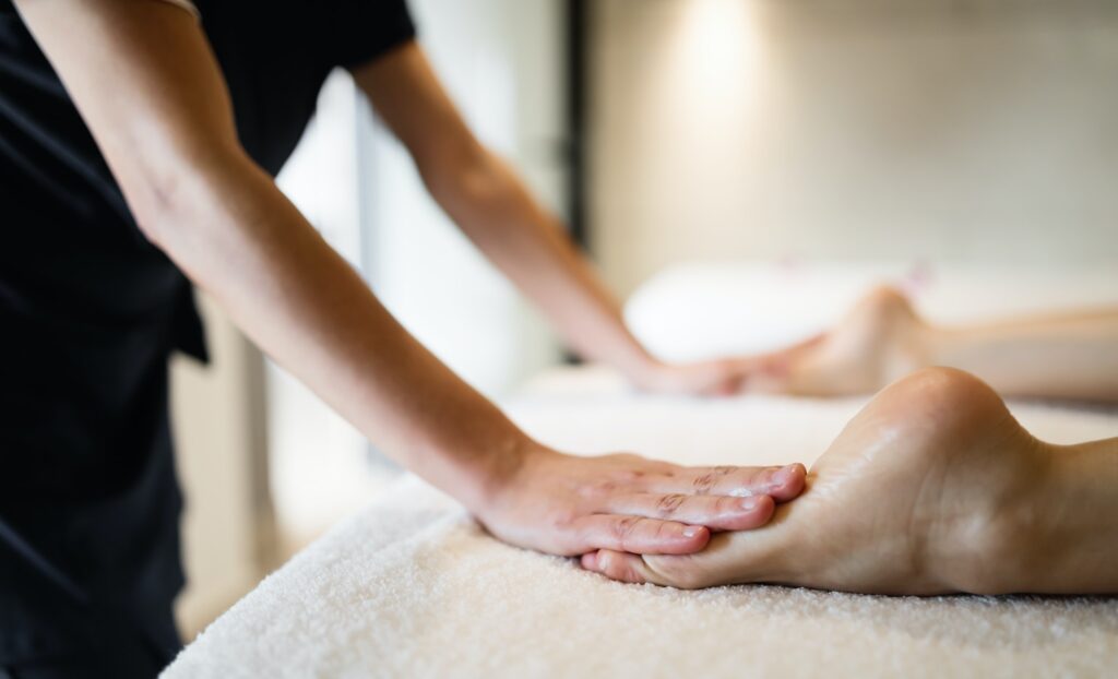 Masseuse masaging feet of person at massage